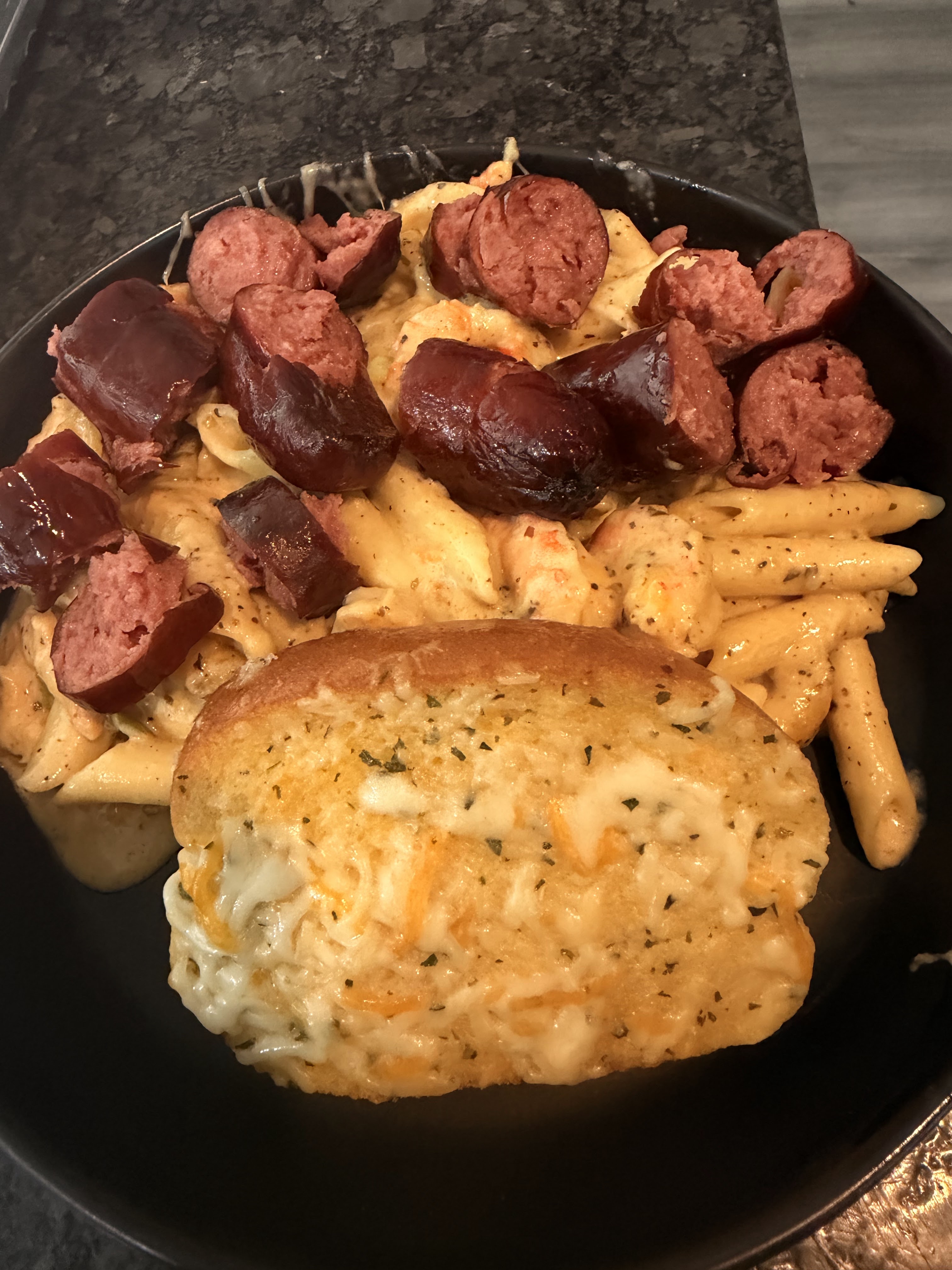 Creamy pasta topped with sausage and served with cheesy garlic bread