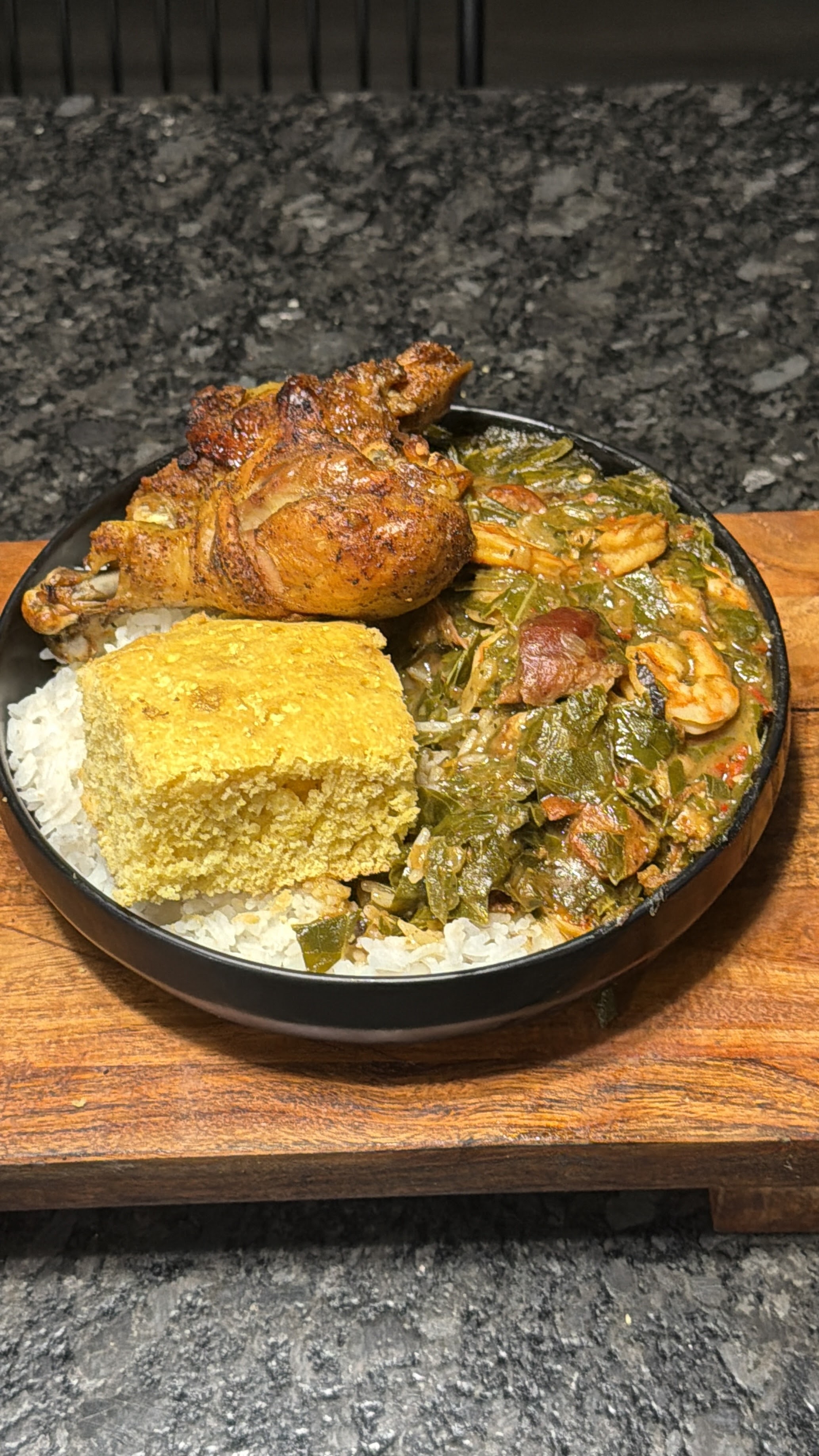 Roasted chicken, greens, rice, and cornbread on a dinner plate