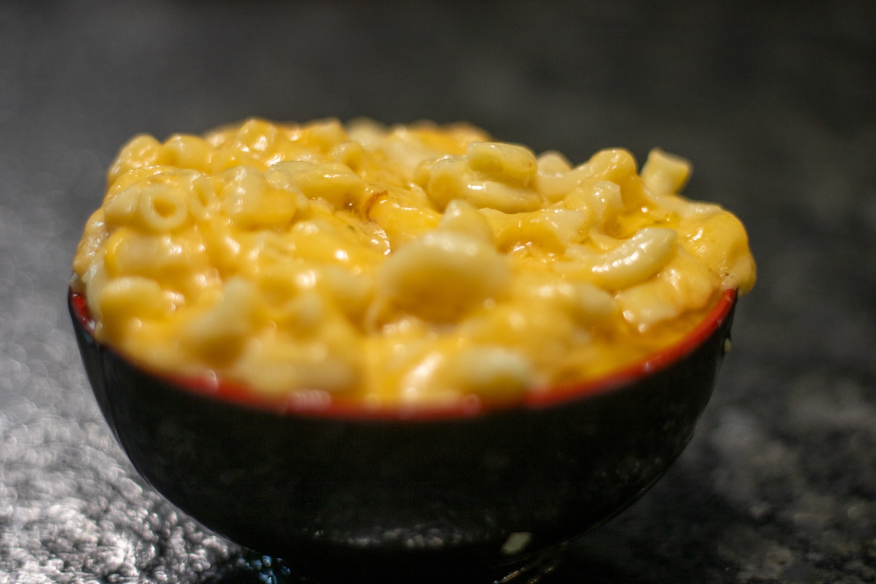 Creamy baked macaroni and cheese in a black serving bowl